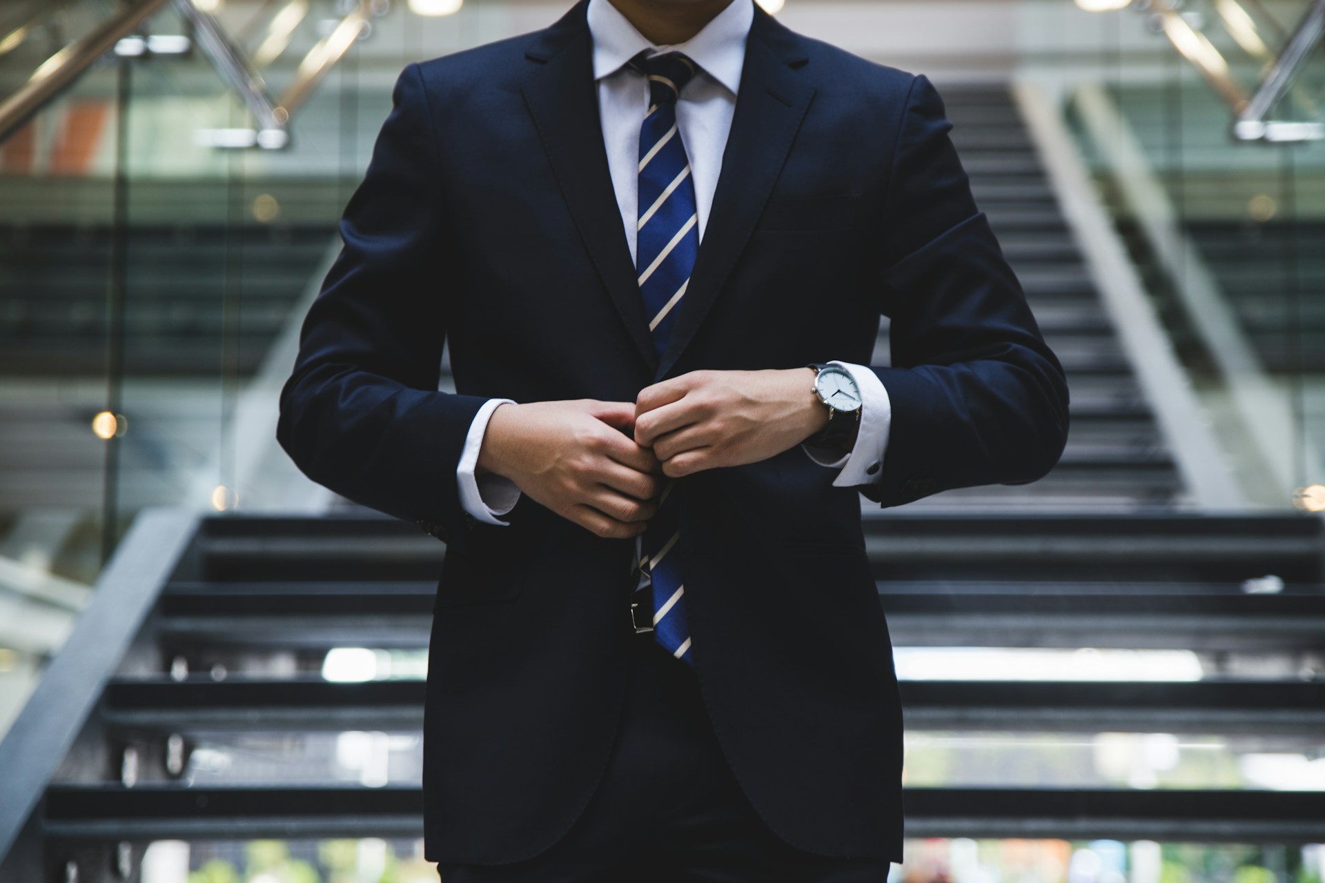 Person in a suit standing by a lot of stairs