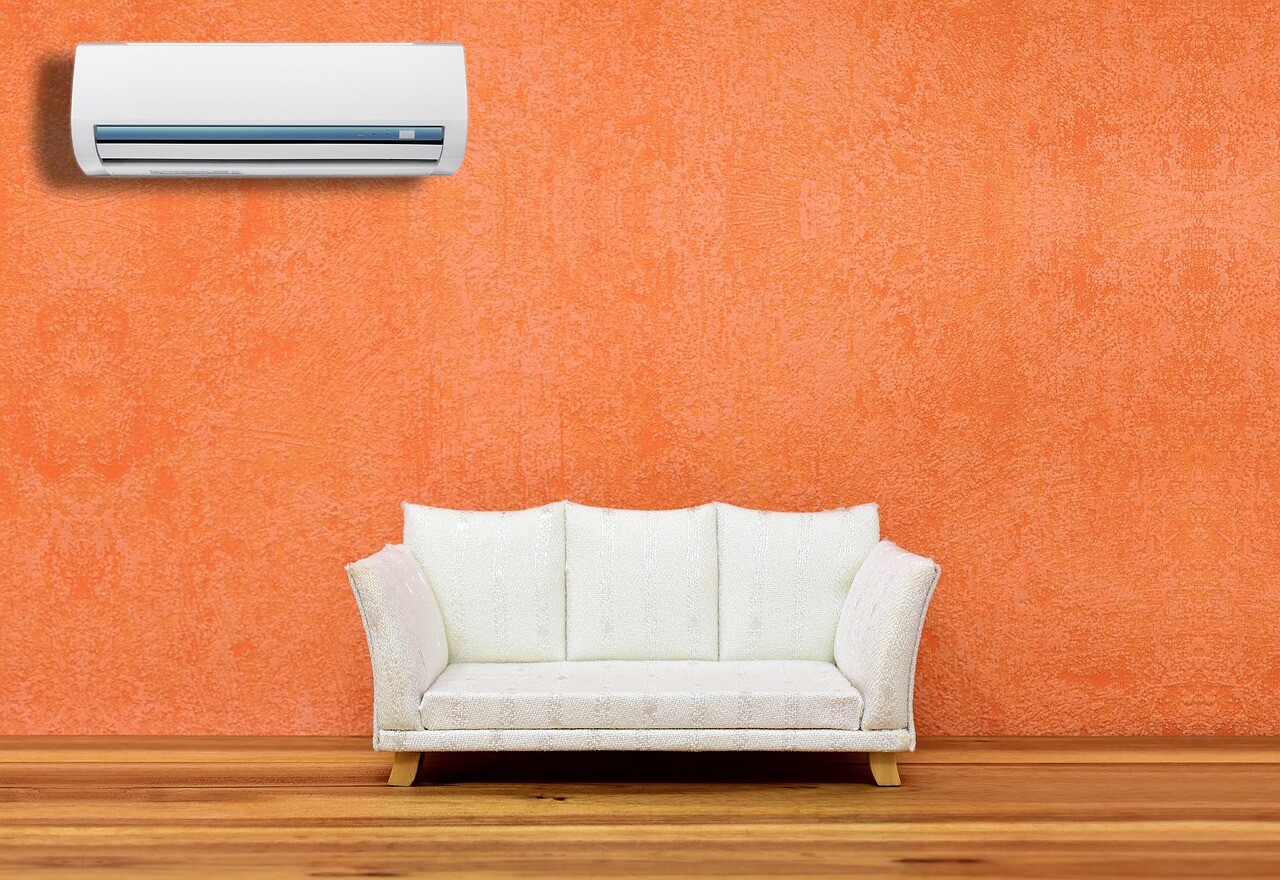 White sofa against an orange wall. A/C unit on wall. Image by Pixabay