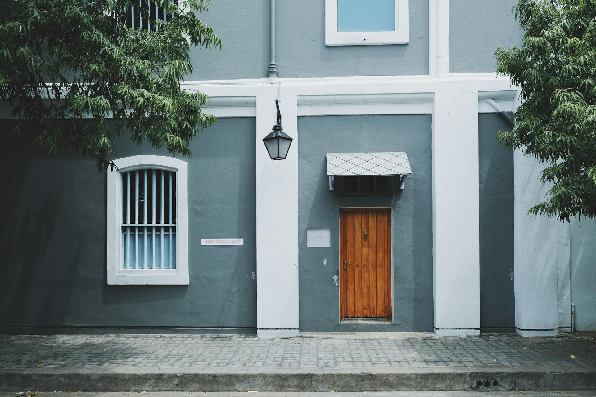 Brown door on a grey/blue and white house. Image by Unsplash
