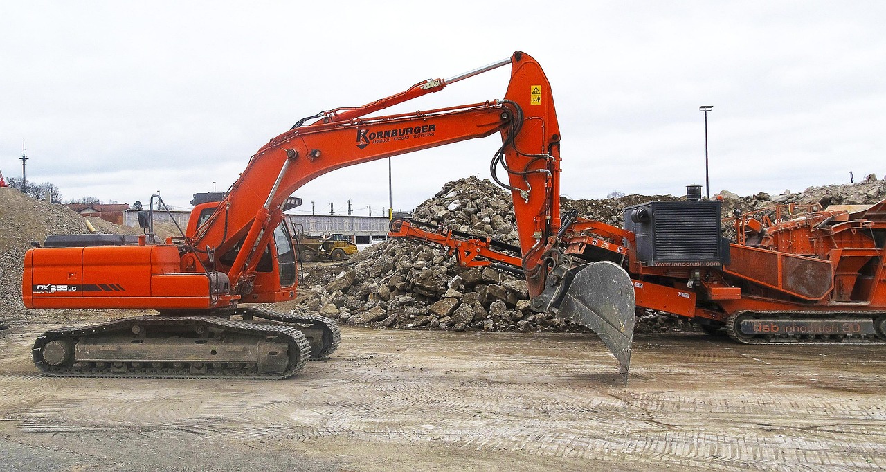 An excavator with a sorting grapple demolishing a building. Image by Pixabay