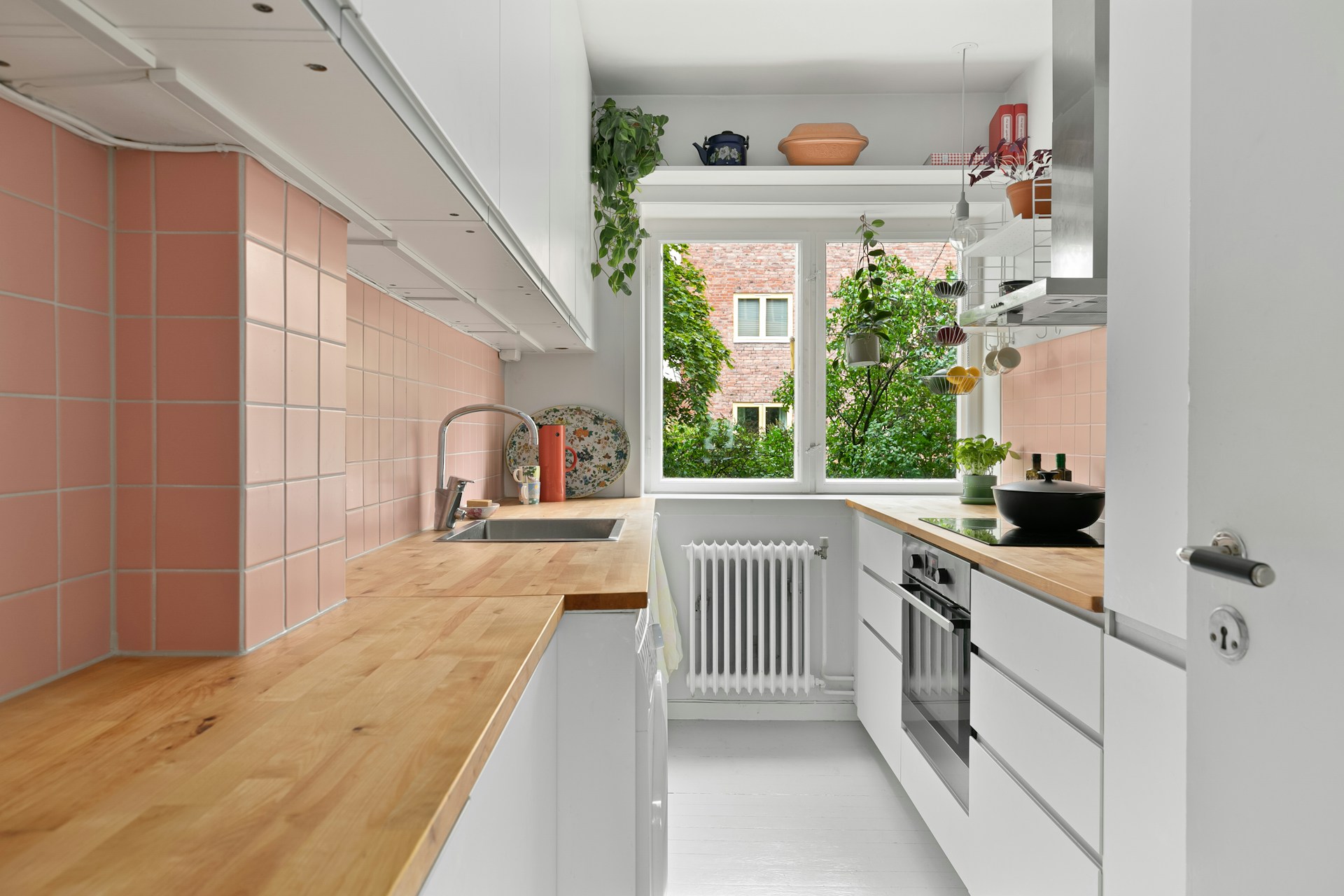 White kitchen with pink backsplash. Image by Unsplash