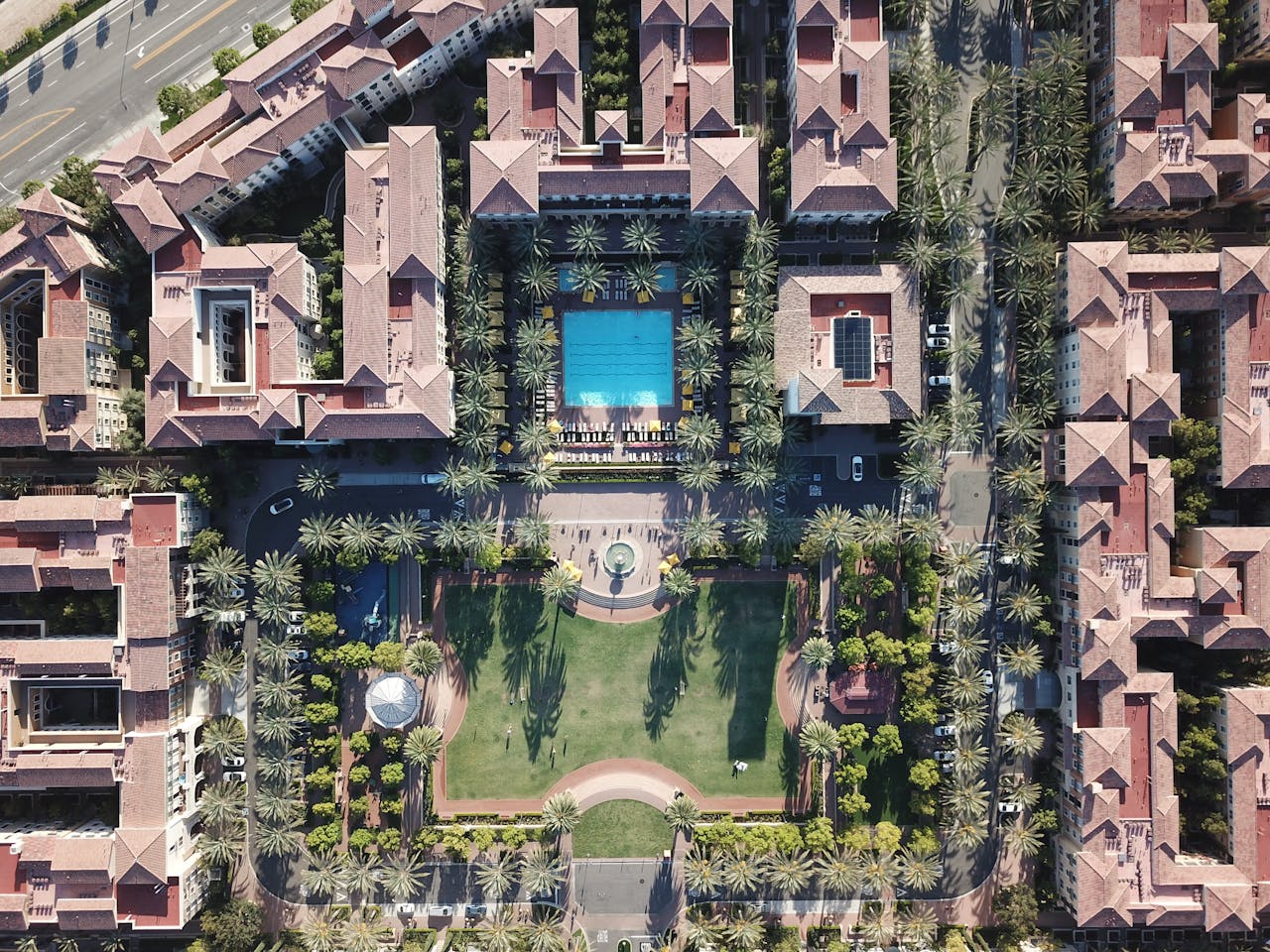 Arial view of houses, palm trees and a pool. Image by Pexels