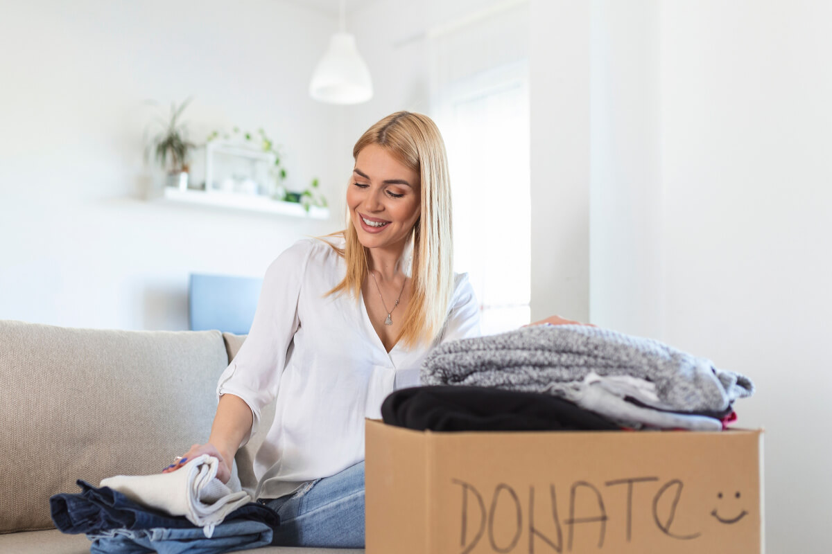 person sorting clothes, putting them in a donation box