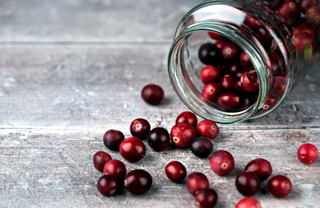 Cranberries in a glass jar and on a table. Image by Unsplash