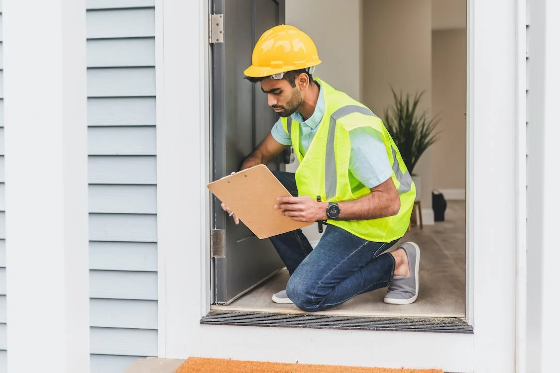 Man in a high-vis jacket holding an inspection checklist and conducting a property inspection