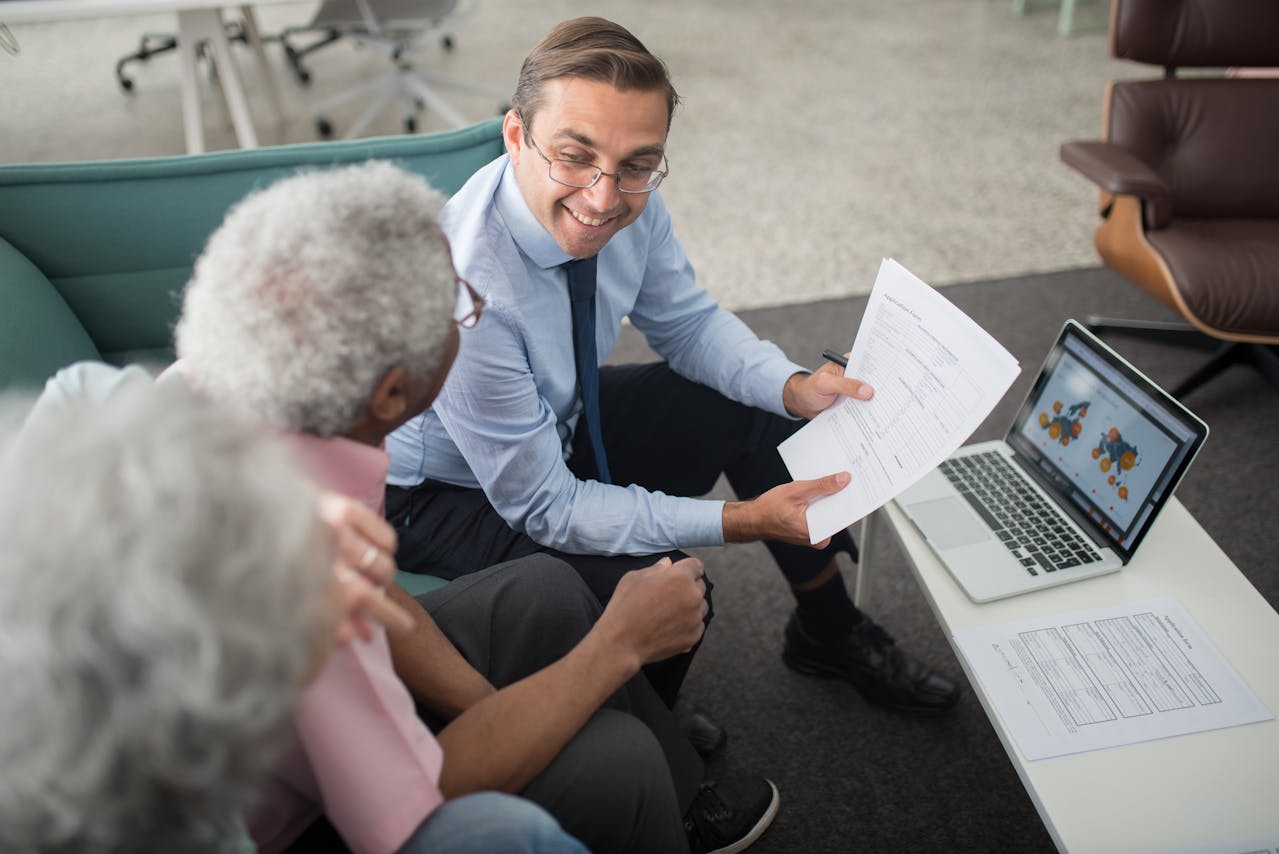 An agent showing documents to elderly people. Image by Pexels
