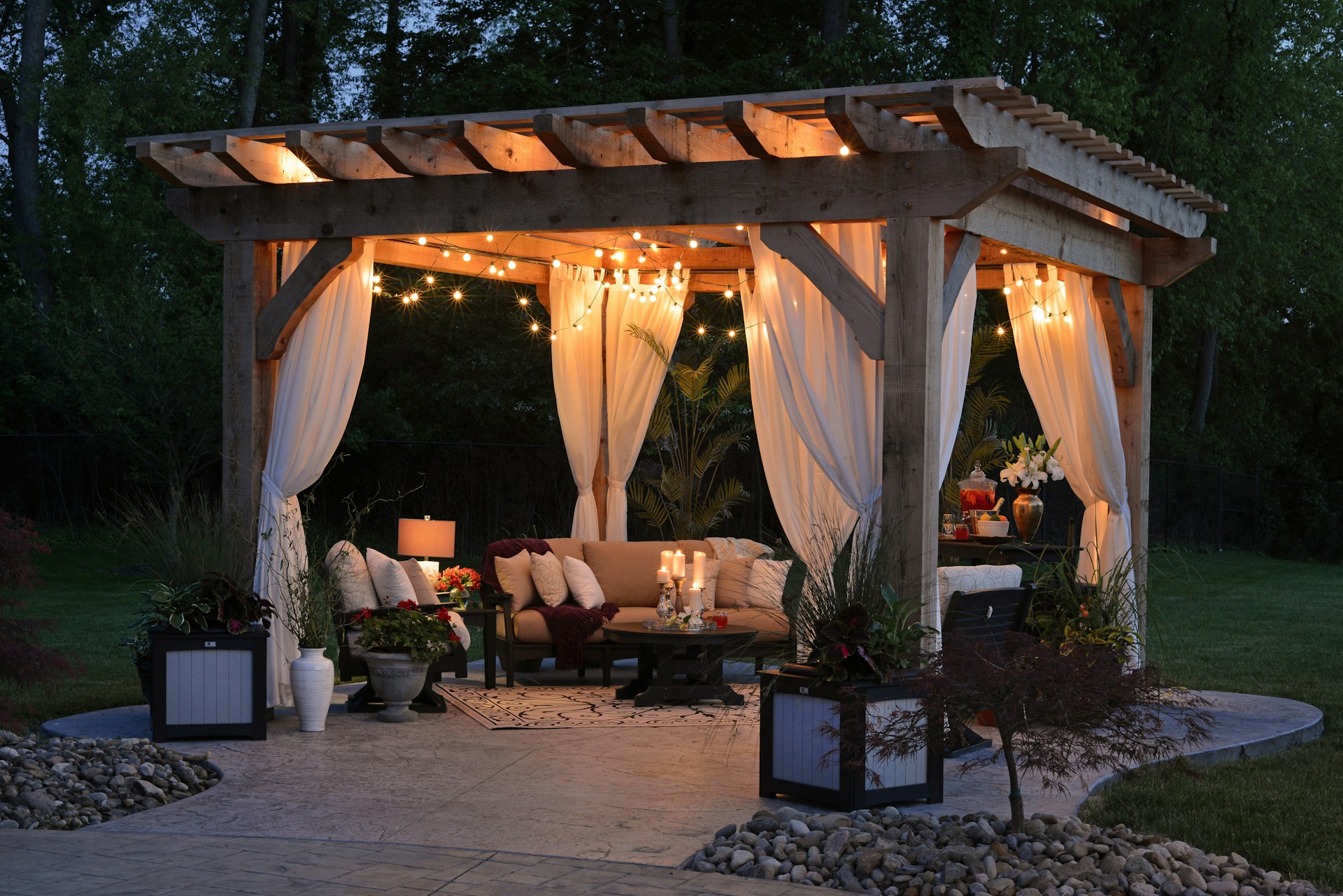 Outdoor gazebo with curtains and string lights and seating. Image by Unsplash