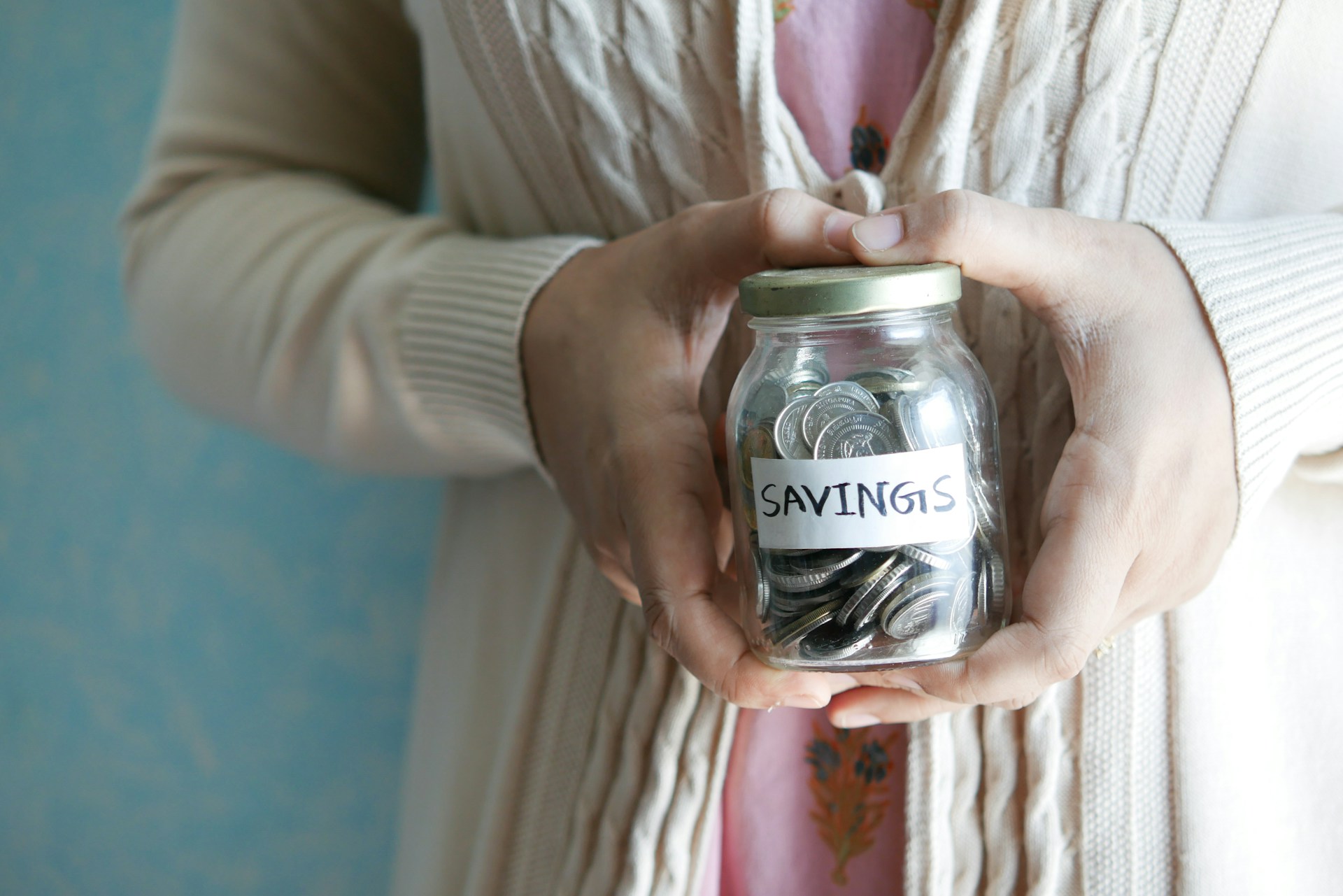 Person holding a jar of coins. Image by Unsplash