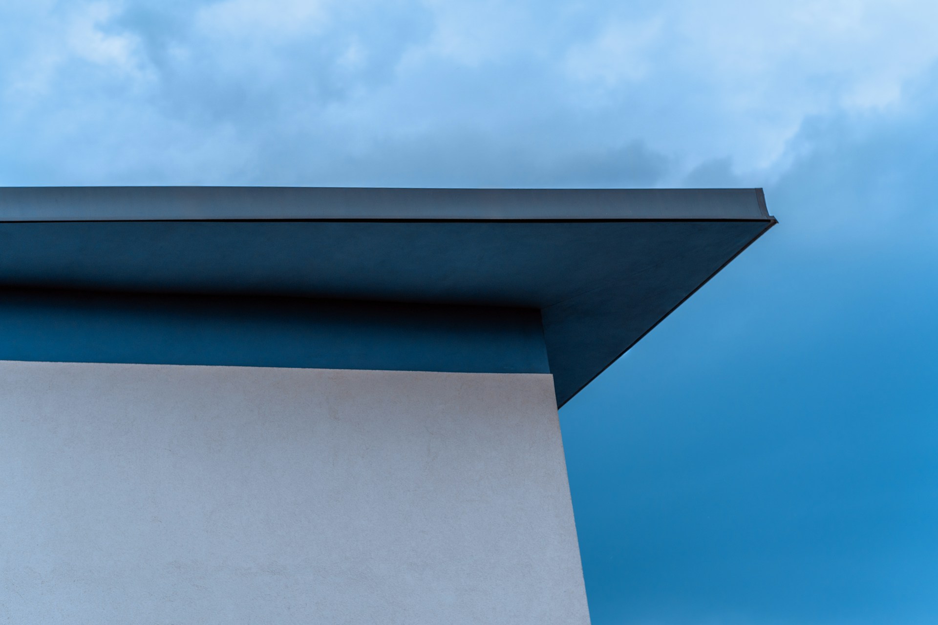 Top of a house, blue sky. Image by Unsplash