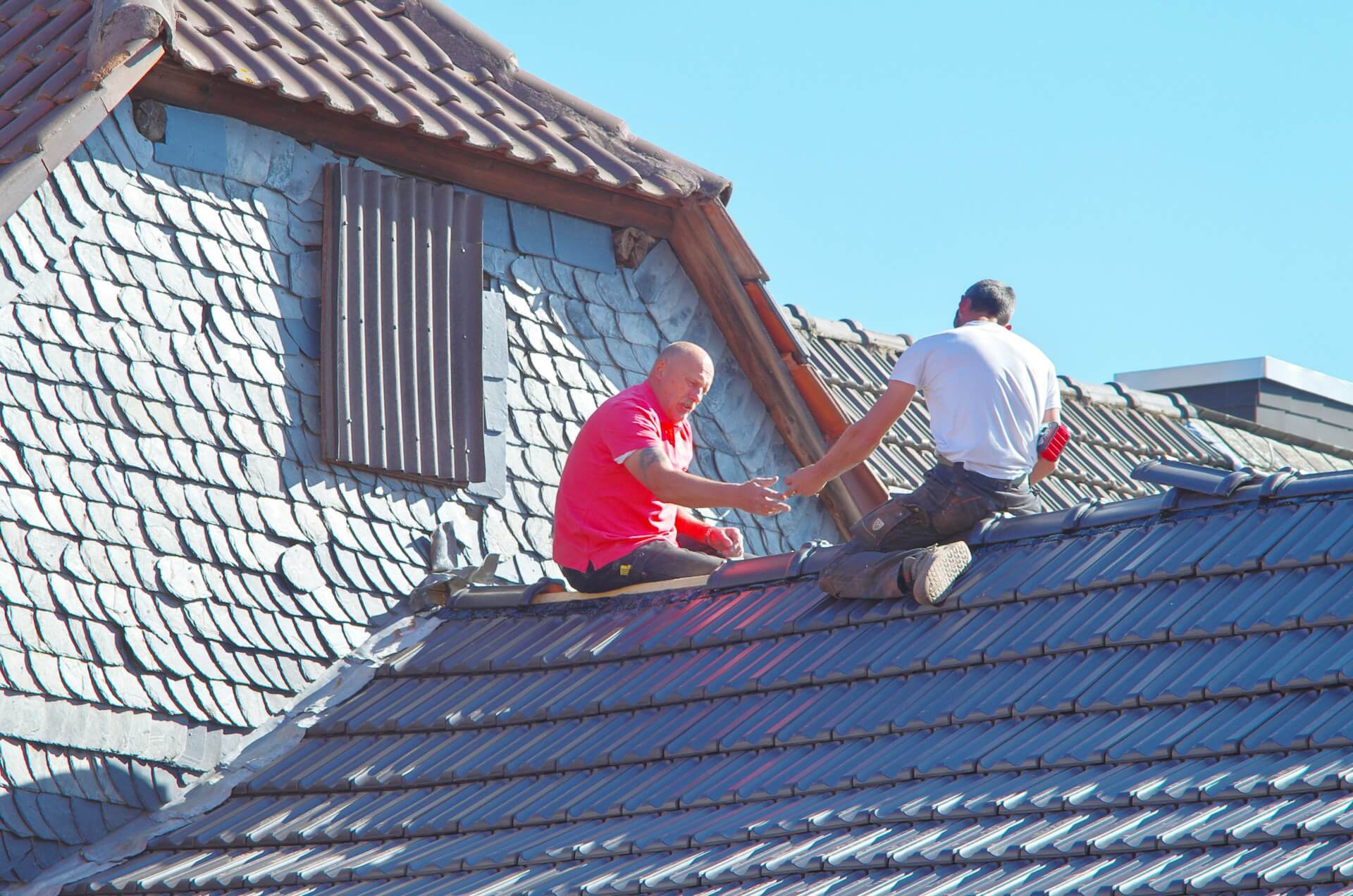 Two men in safety gear working on the roof of a house. Image by Unsplash
