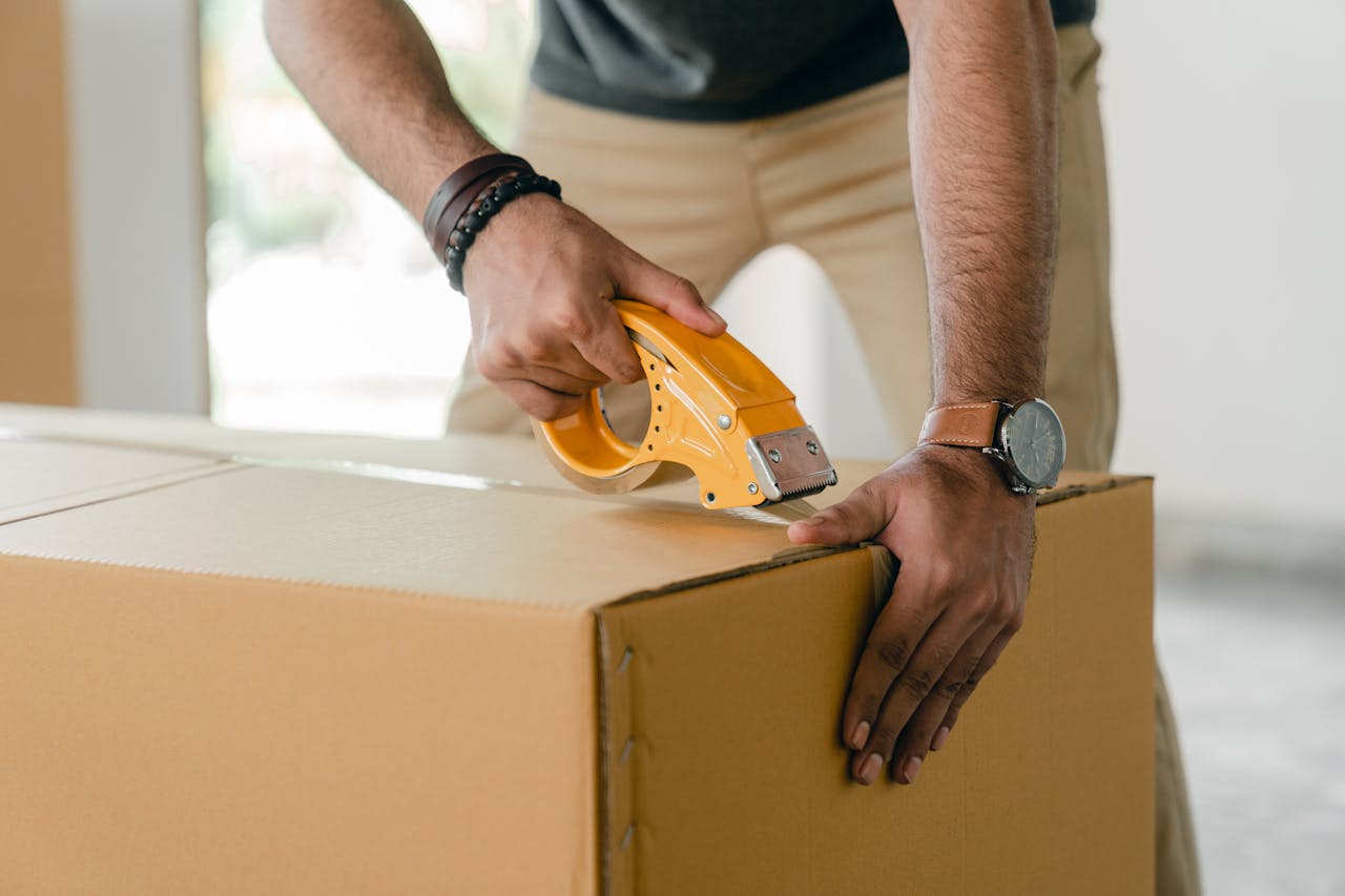 Person taping a box. Image by Pexels