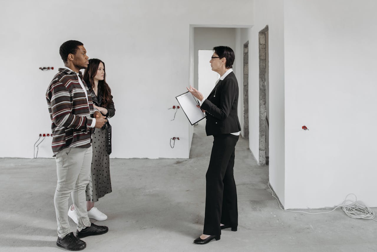 a broker inside a house talking to a couple of people. Image by Pexels
