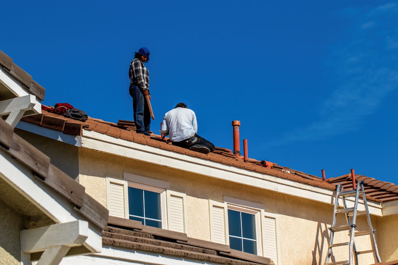 2 people repairing a roof. Image by Pexels