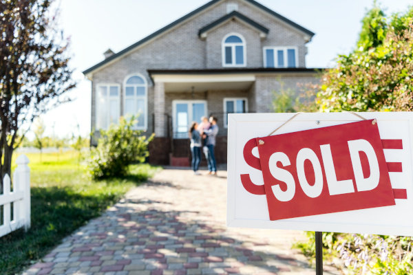 Sold sign in front of a house, people in the background